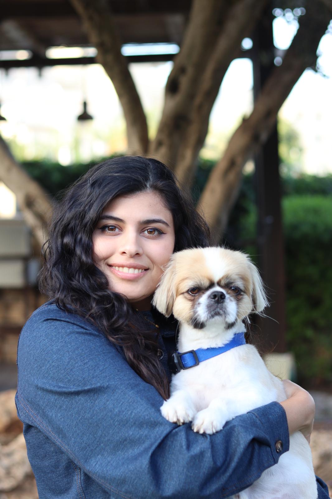 Samar Abu Hegly smiling outdoors, holding her dog Mario